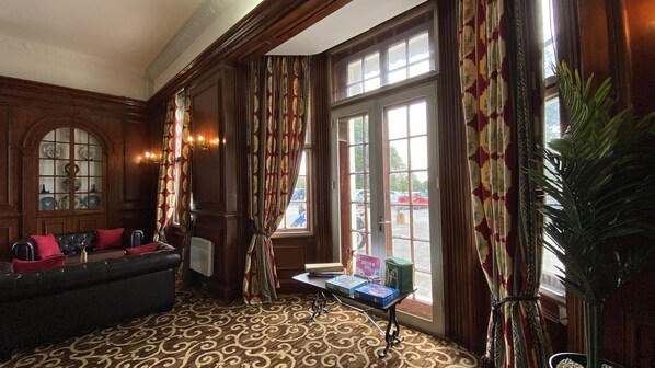 Relax in a cozy space with a plush sofa, ornate curtains, and a potted plant.