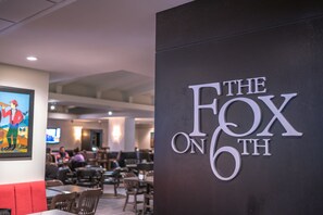 Enjoy a casual dining experience at THE FOX ON 6TH, where framed artwork and comfortable seating create a welcoming atmosphere.