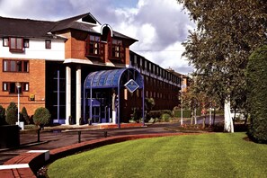 Welcome to the Cothron Hotel, featuring a grand entrance with a covered walkway and beautifully landscaped surroundings.