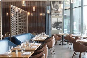 Enjoy dining in a stylish space with booths and individual tables, framed photographs, and pendant lighting.