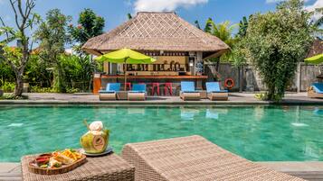 Relax by the pool surrounded by lush greenery and enjoy a casual meal at the thatched-roof bar.