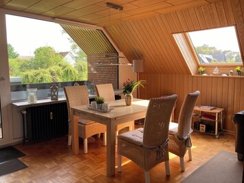 Esstisch im Wohnzimmer mit großer
Panoramascheibe und Tür zum Logia- Balkon