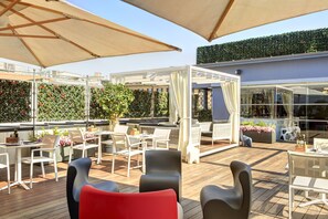 Relax on the outdoor patio with comfortable seating, umbrellas, and a trellis with lush greenery.