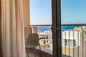 Enjoy the breathtaking sea view from this balcony with a metal railing and a single chair.